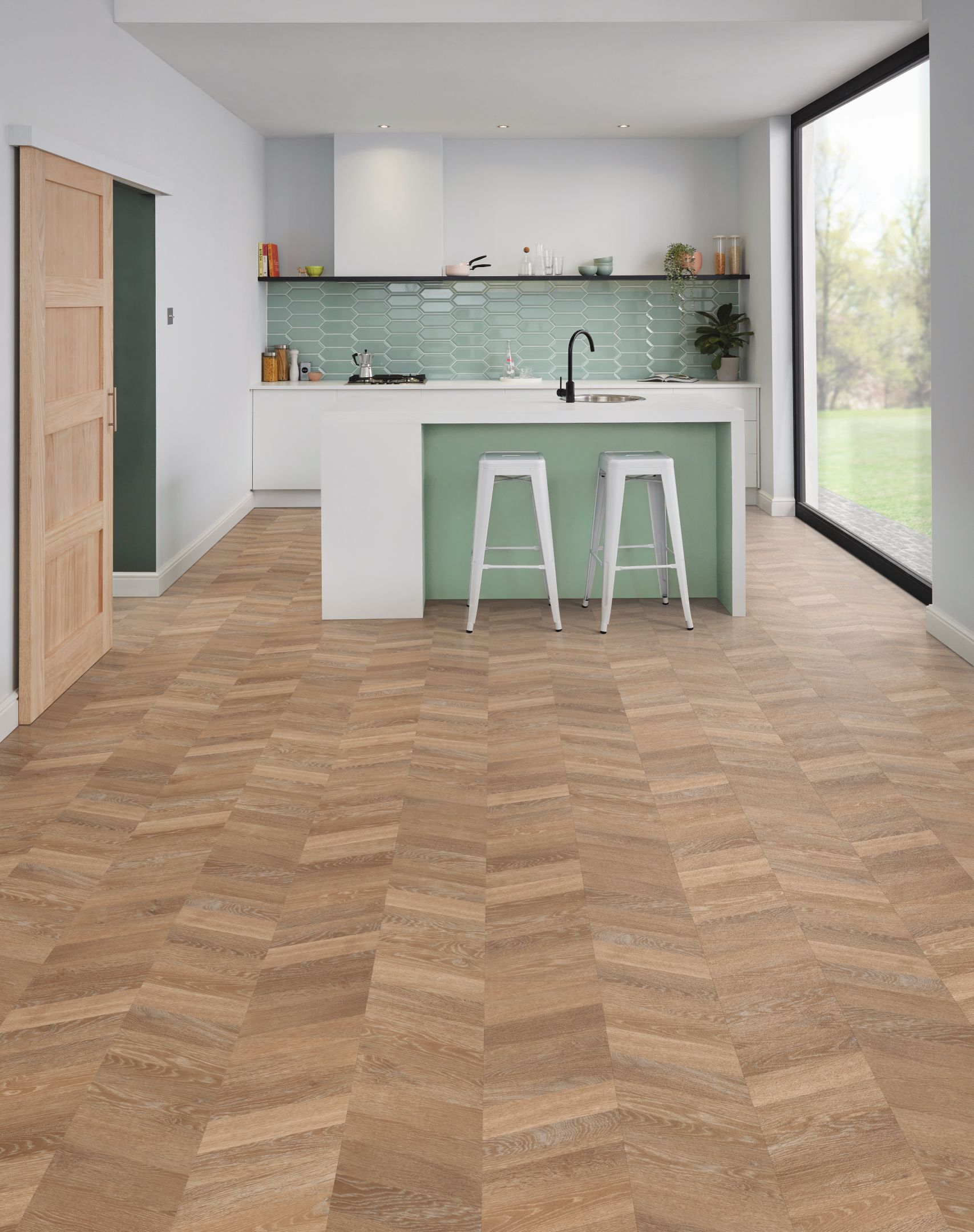 Seafoam and white kitchenette and island with brown woodgrain LVP floor installed in chevron design