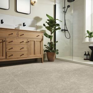 Bathroom featuring square grouted neutral stone tiles, wooden double sink vanity, houseplant, and tiled shower with glass door