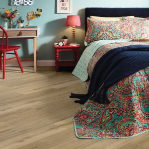 Vibrant bed, nightstand, and desk, with mid brown plank flooring installed on a diagonal