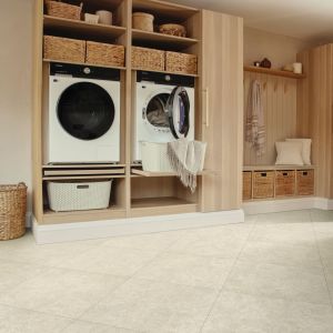 Warm, clean laundry and utility space with cream tile floor, built-in washer and dryer, shelving fitted with baskets