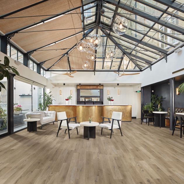 Commercial space featuring domed skylights, glass orb light fixture, brushed gold counter, and various chairs and couches dispersed across beige woodgrain floor
