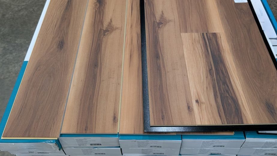 Pallet of teal and white cartons of LVP flooring with Smoked Amber planks and sample on top